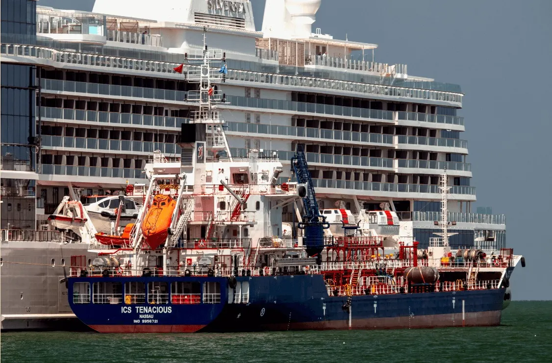 ICS Tenacious made fast alongside a cruise ship with her hoses rigged.