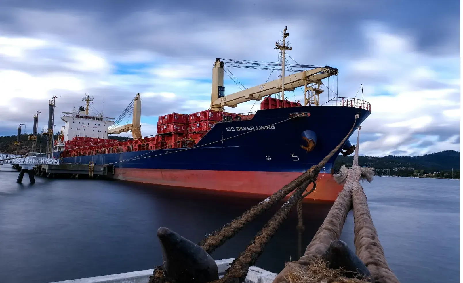 ICS Silver Lining moored at a wharf at dusk, mooring lines running to a bollard in the foreground.