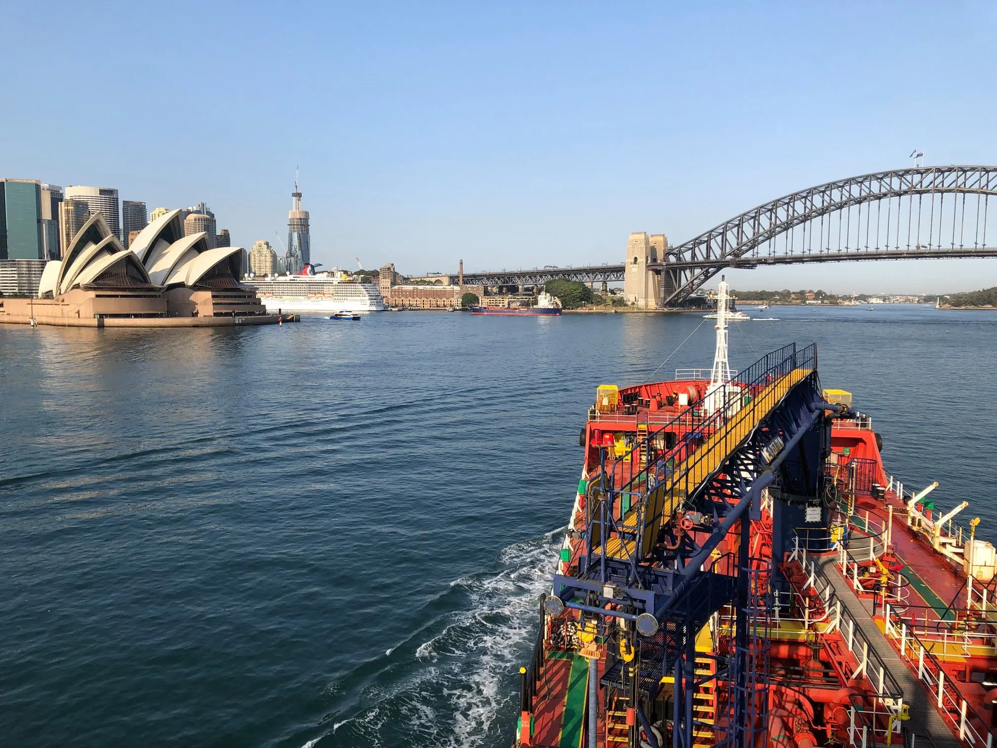 Looking forward from a tanker’s deck on Sydney Harbour, with the Opera House, the city and the Harbour Bridge across the water.