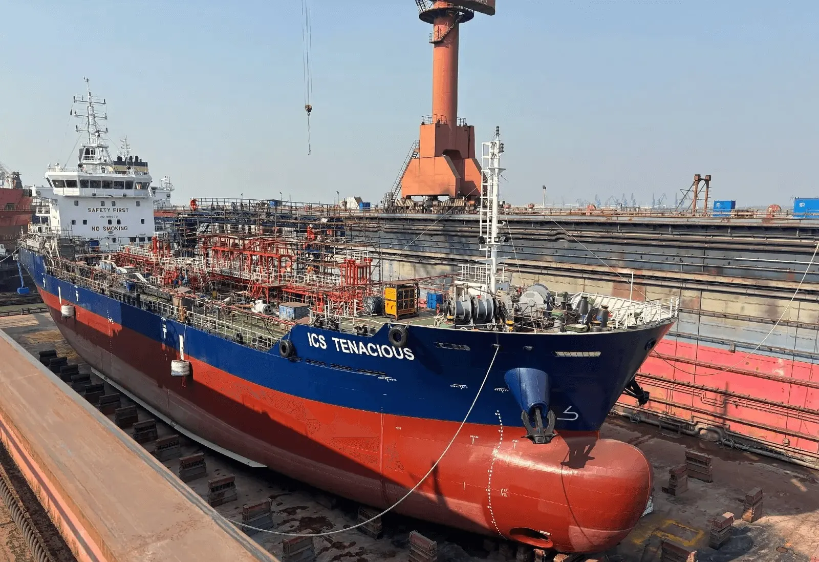 ICS Tenacious standing in dry dock with her red underwater hull and bulbous bow uncovered.