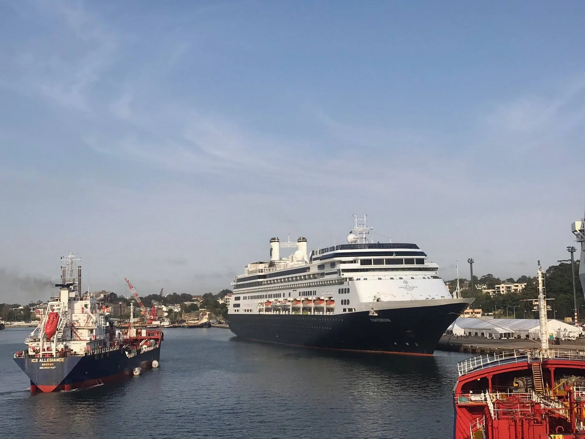 ICS Allegiance at work in a harbour with a cruise ship moored across the water.