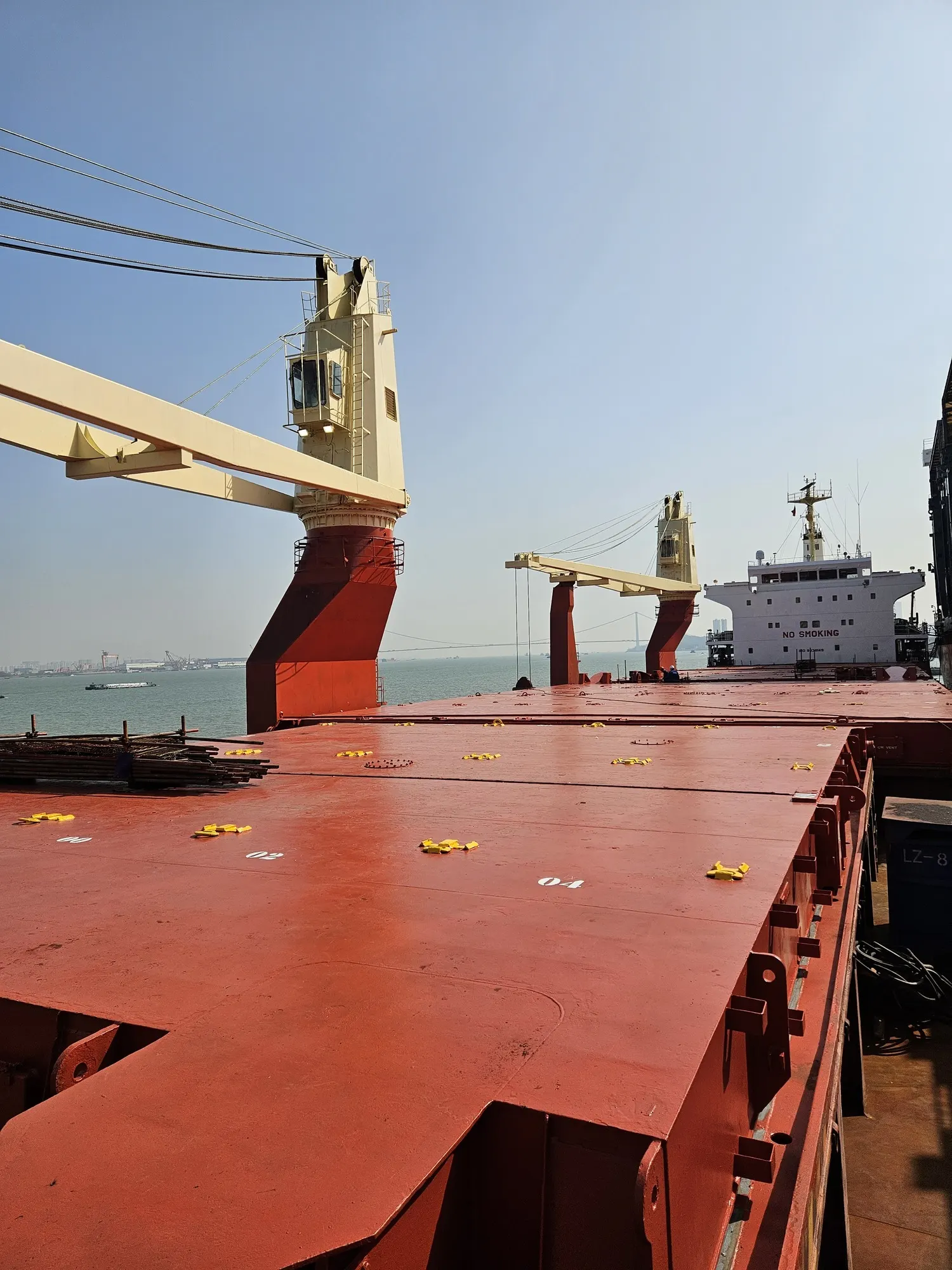 The red hatch covers and a cream deck crane seen looking forward along the main deck from the accommodation.